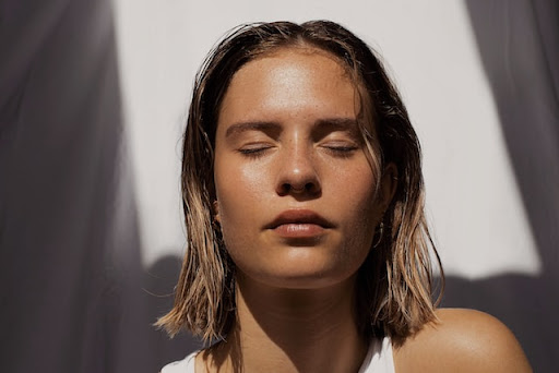 Une femme fermant les yeux et qui sait comment hydrater sa peau sèche