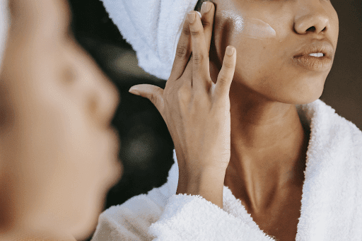 Femme qui applique une crème de jour et de nuit devant son miroir.
